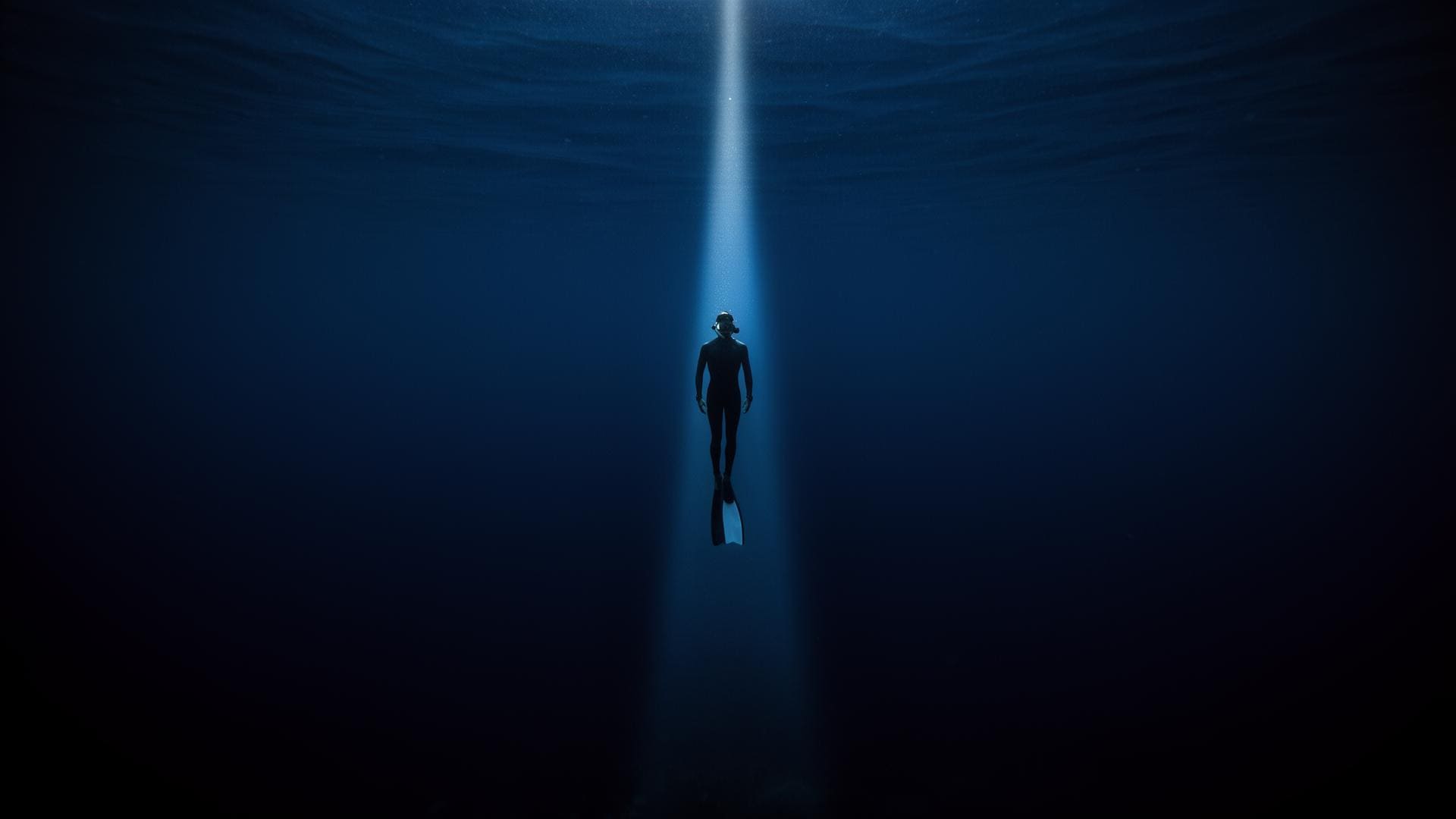 Freediver descending into the deep blue